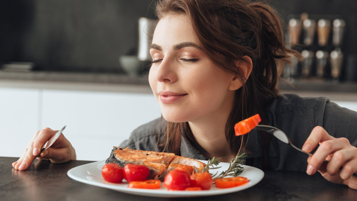 mulher segurando garfo e faca enquanto sente o aroma de um prato de comida - olfato