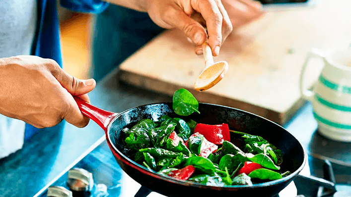 Pessoa cozinhando vegetais em uma frigideira - saúde mental