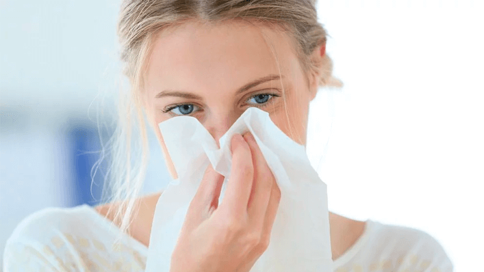 Mulher segurando lenço e assoando o nariz - rinite